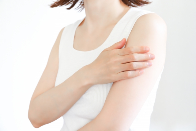 腕を抑えながら手術中やダウンタイム期間中に現れる症状を説明する女性