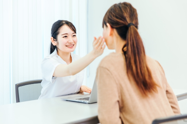 顔の脂肪吸引のダウンタイムを短縮するための過ごし方を説明する女性の頬に手を当てて確認する看護師
