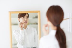 鏡を見て頬を触る女性01