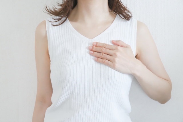 シリコンバッグ豊胸のダウンタイムが長引くケースを説明する胸に手を当てている女性