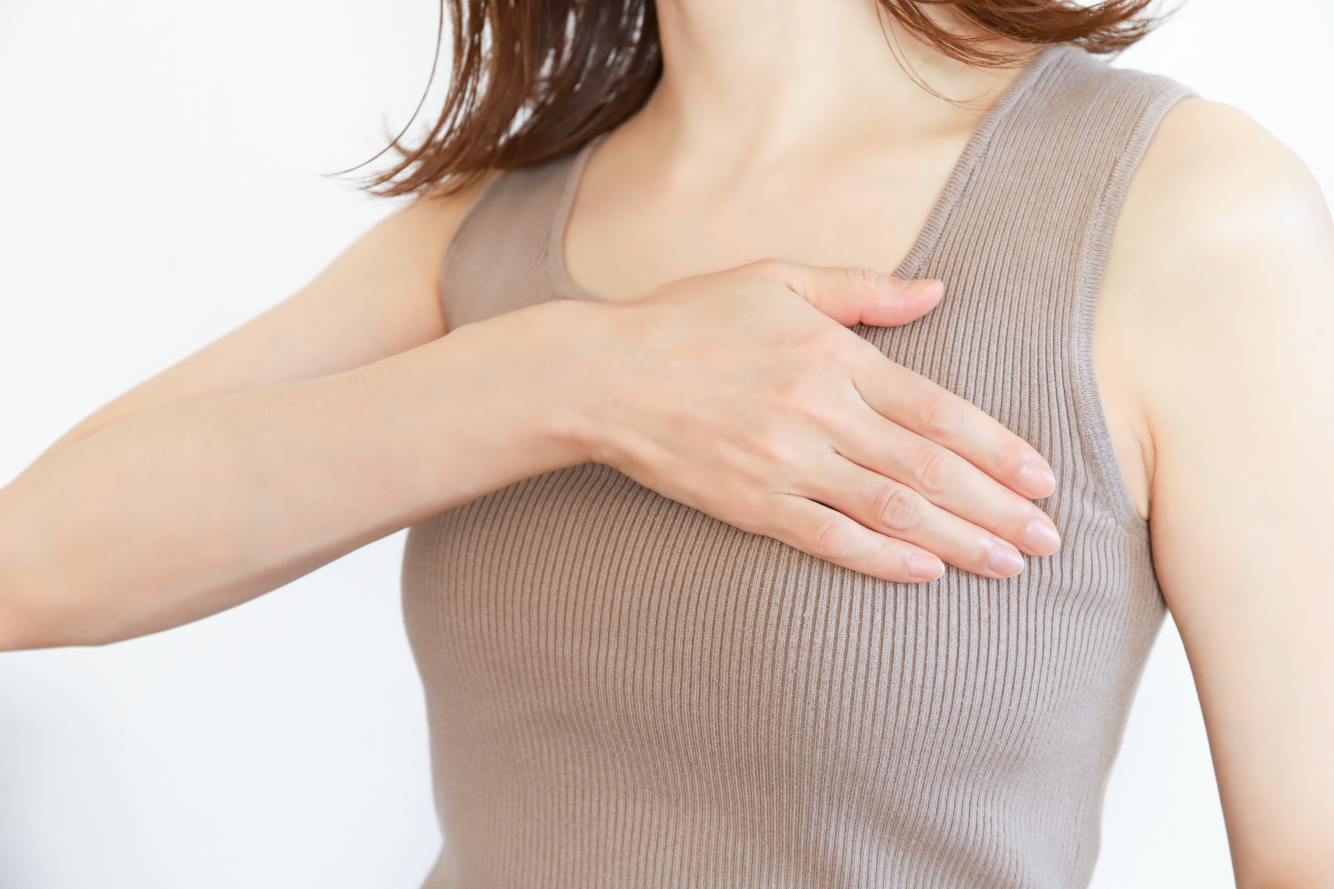 シリコンバッグ豊胸のダウンタイム中に現れる症状を説明する片手で胸を抑える女性