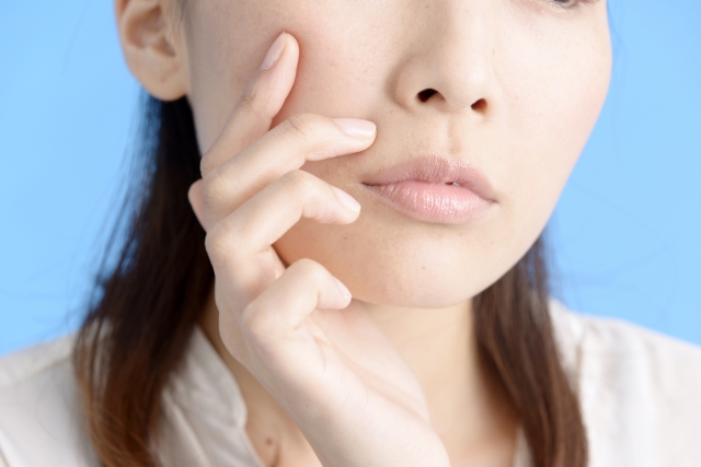 手を頬に当てながら鼻整形でクリニックを選ぶときのポイントを考える女性