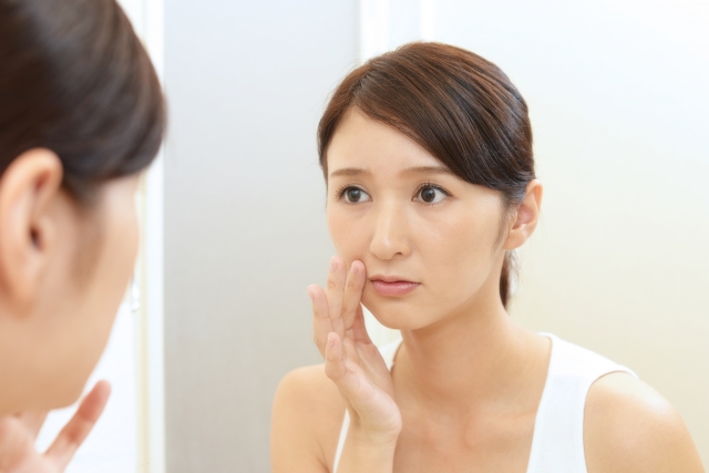 鏡を見ながらブルドッグ顔の改善にセルフケアは有効かを確認する女性