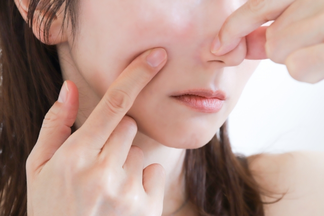 顔の肌を指で触る女性