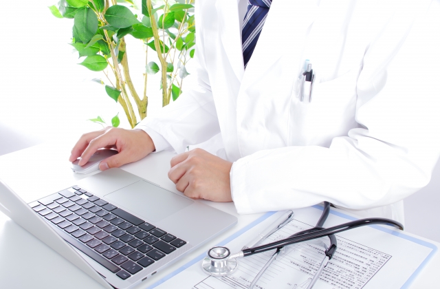 白衣を着た医師がパソコンとマウスを使う様子