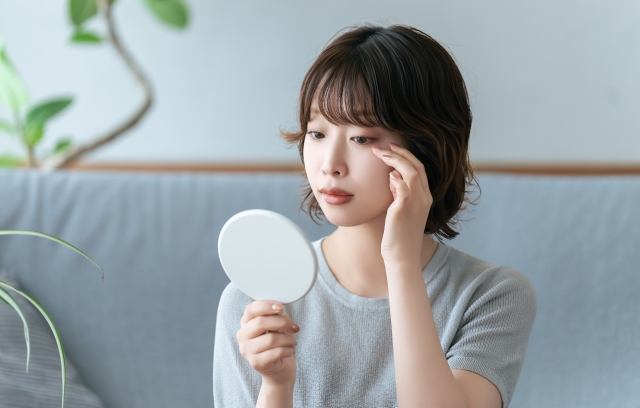 鏡で目元を確認する女性