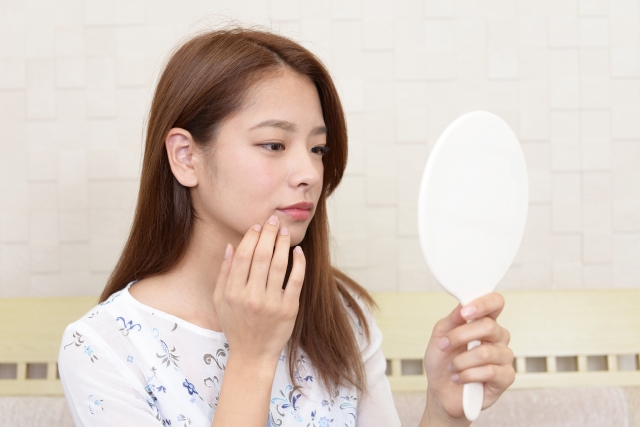 鏡で顔の様子を確認する女性