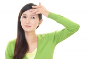 おでこを触る女性