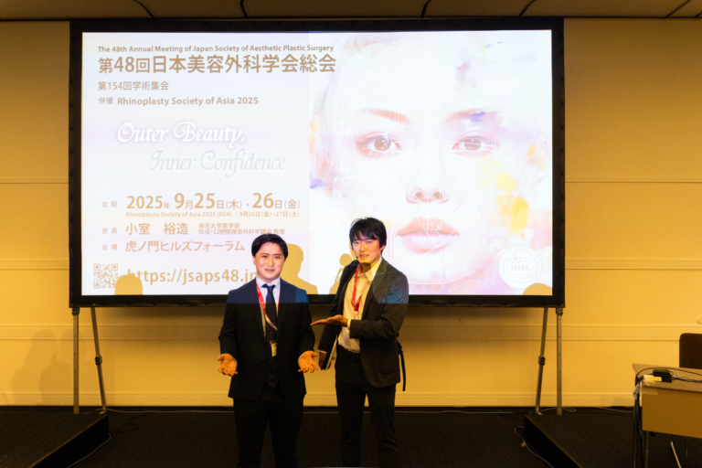 学会発表をする2人の男性とスクリーン