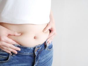 お腹周りの脂肪をつまむ女性