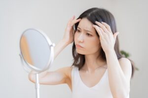 鏡でおでこを確認する女性