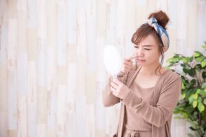 鏡で鼻を気にする女性