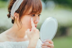女性が鏡を見て目元を指差す