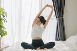 ベッドの上でストレッチする女性