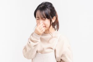 鼻をつまんで目を閉じている女性