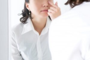 鏡の前で片目を触る女性