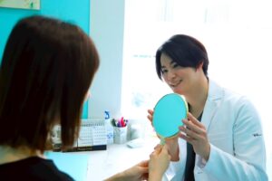 医師が女性患者に手鏡を渡している様子