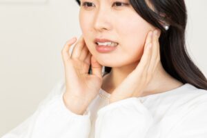女性が耳のあたりに手を当てている