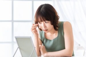 鏡で顔を見るショートヘアの女性