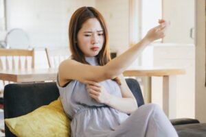ソファに座り二の腕を触る女性