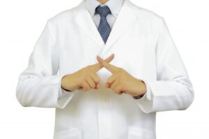 白衣を着た人物が腕を交差させている