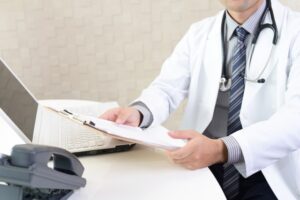 白衣の医師がカルテを見ている様子