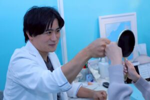 白衣の男性が女性に手鏡を渡している