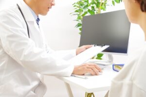 診察室でパソコンを操作する医師と患者