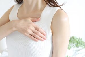 白い服を着た女性が胸に手を当てている様子