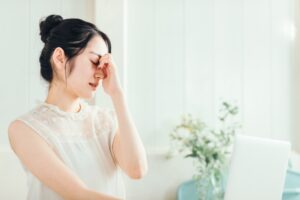 女性が目頭を押さえて悩んでいる