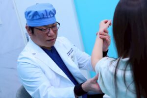 白衣の医師が患者の腕を診察する様子
