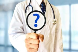 医者が虫眼鏡で疑問符を拡大