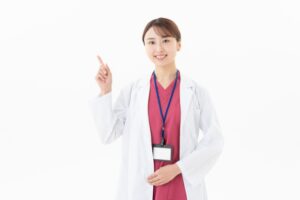白衣を着て笑顔で指差しする女性医療従事者