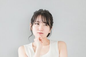 顎に手を当てて考えごとをする女性