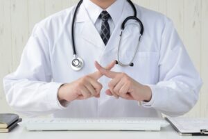 腕を組んでバツ印を示す白衣の男性医師