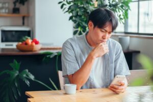 スマホを見て考え込む男性