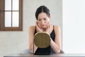 鏡を見ながら顔に触れる女性