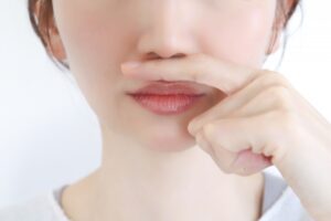 唇に指を当てる女性の顔のアップ