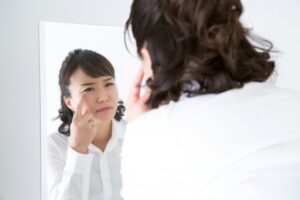 鏡で目元をチェックする女性