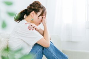 ソファに座り片手で顔を覆う女性