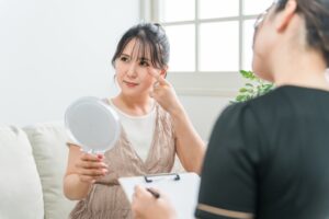 鏡を見ながら目の下を指差す女性と説明する女性