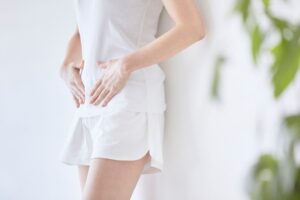 お腹に手を当てて立つ女性