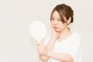 鏡をみて自分の顔を気にする女性