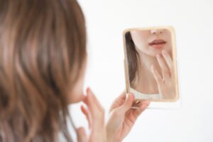 鏡で自分の顔を見る女性
