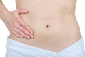 女性のへそと腹部に置かれた手