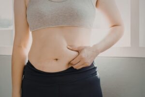 下腹部のぜい肉をつまむ女性